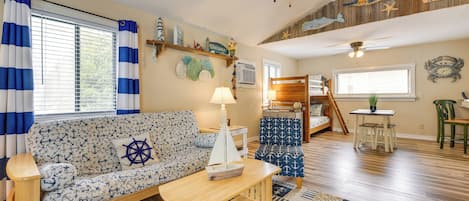 A nautical-themed living room with a sofa, coffee table, and a small sailboat model.