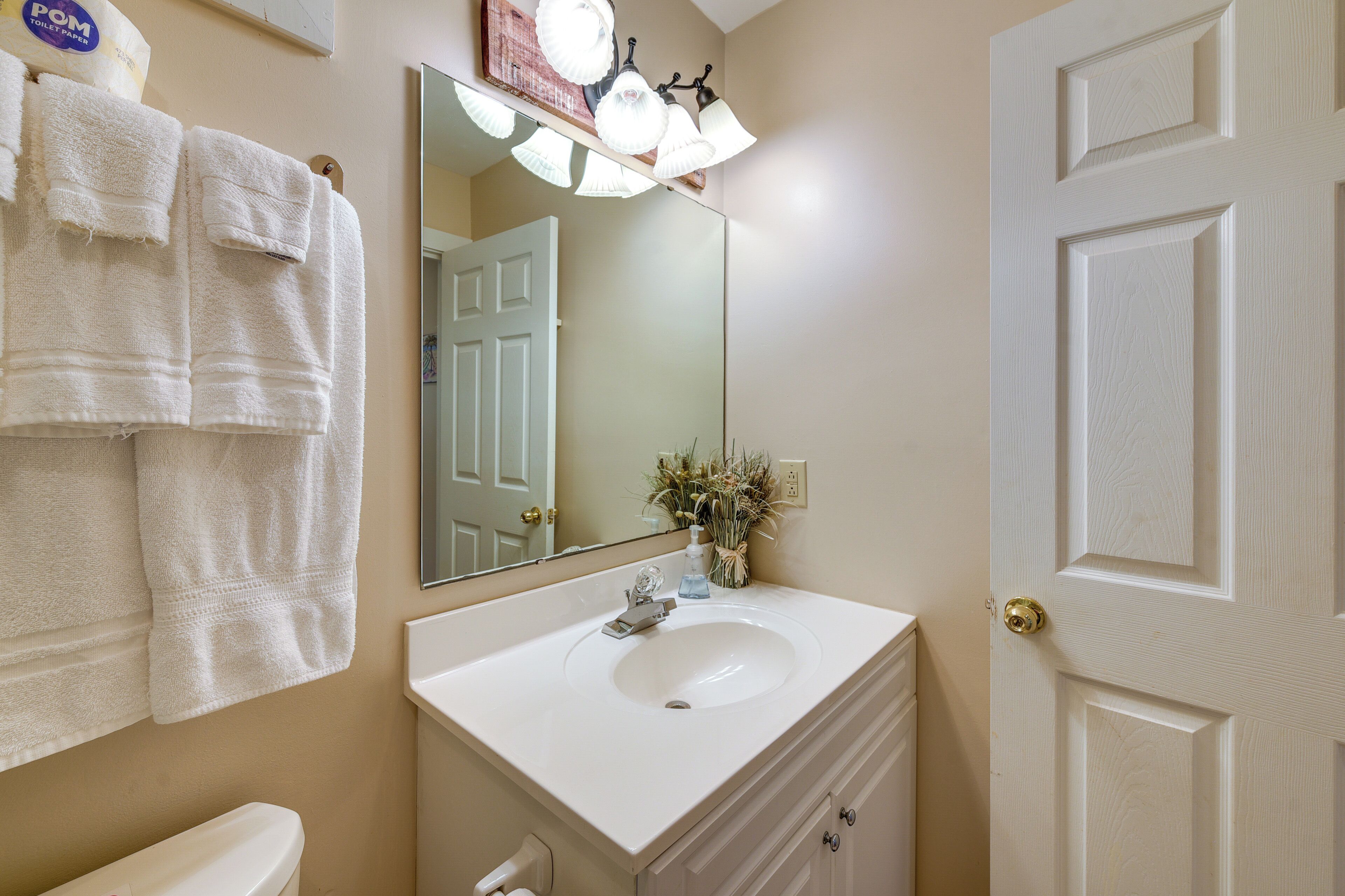 A bathroom with a white sink, a mirror, a towel rack with towels, and a door.