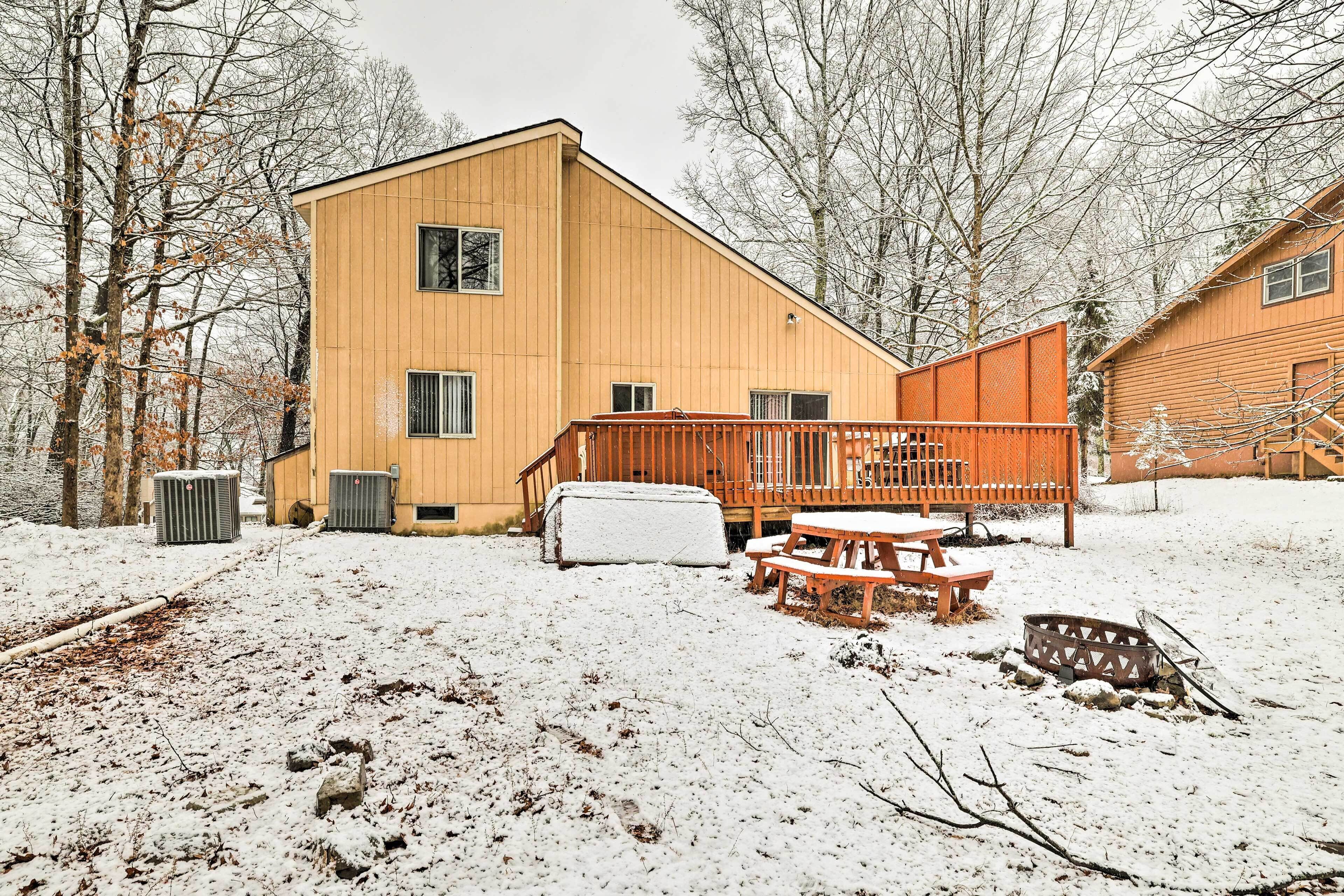 Une cabane en bois avec une terrasse, une table de pique-nique couverte et un foyer.