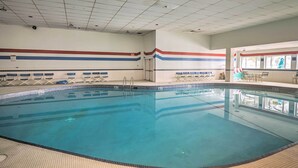 Piscina interna com piso ladrilhado, água azul cristalina e teto com iluminação embutida.