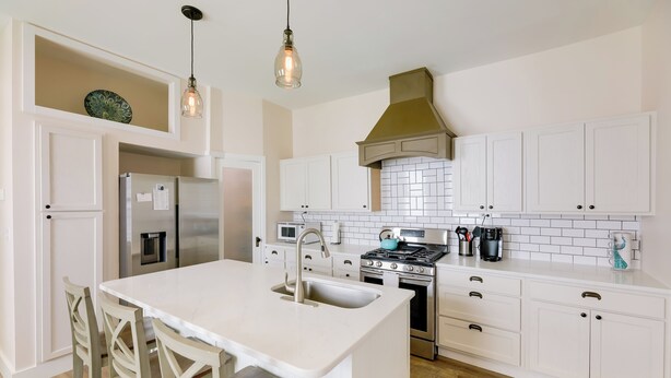 A modern kitchen with white cabinetry, a central island with bar stools, stainless steel appliances, and pendant lighting. - Historic Madison Retreat - 1 Mi to Ohio River (Madison)