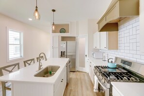 A modern kitchen with a central island, stainless steel appliances, and pendant lighting.