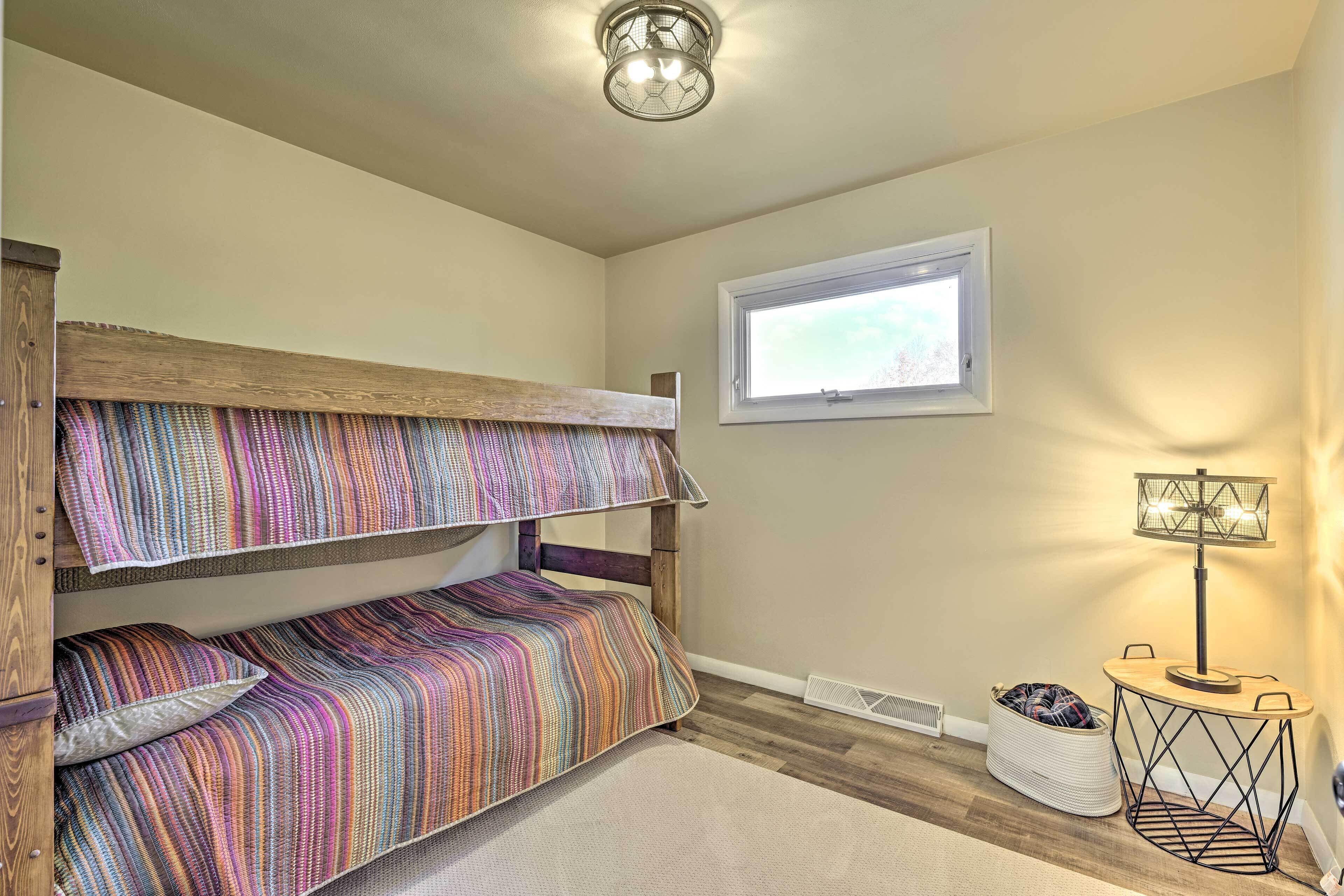 Une chambre avec un lit superposé, une table de chevet avec une lampe, une fenêtre et un radiateur.