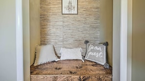 Un pasillo con pared de madera, un cuadro enmarcado y tres cojines decorativos.