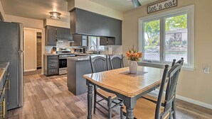 Una cocina moderna con armarios oscuros, una isla central y un comedor con mesa y sillas de madera.