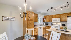 Uma cozinha com armários de madeira, uma placa rústica, um lustre e um espaço de refeições com mesa e cadeiras.