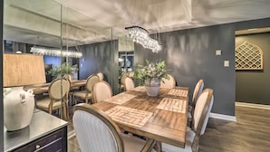Un comedor con una mesa de madera, sillas, una araña y una planta en maceta.