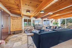 A cozy living room with a large sofa, wooden ceiling beams, and a television. - Hot Tub + Scenic Views: Luxury Twain Harte Cabin! (Twain Harte)