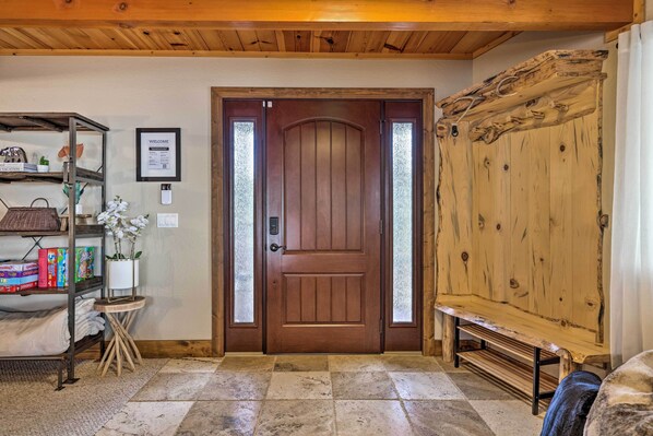 A wooden door with a welcome sign, a bench, and a shelf with books and a plant. - Hot Tub + Scenic Views: Luxury Twain Harte Cabin! (Twain Harte)