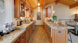 A kitchen with wooden cabinets, granite countertops, and a central island. - Hot Tub + Scenic Views: Luxury Twain Harte Cabin! (Twain Harte)