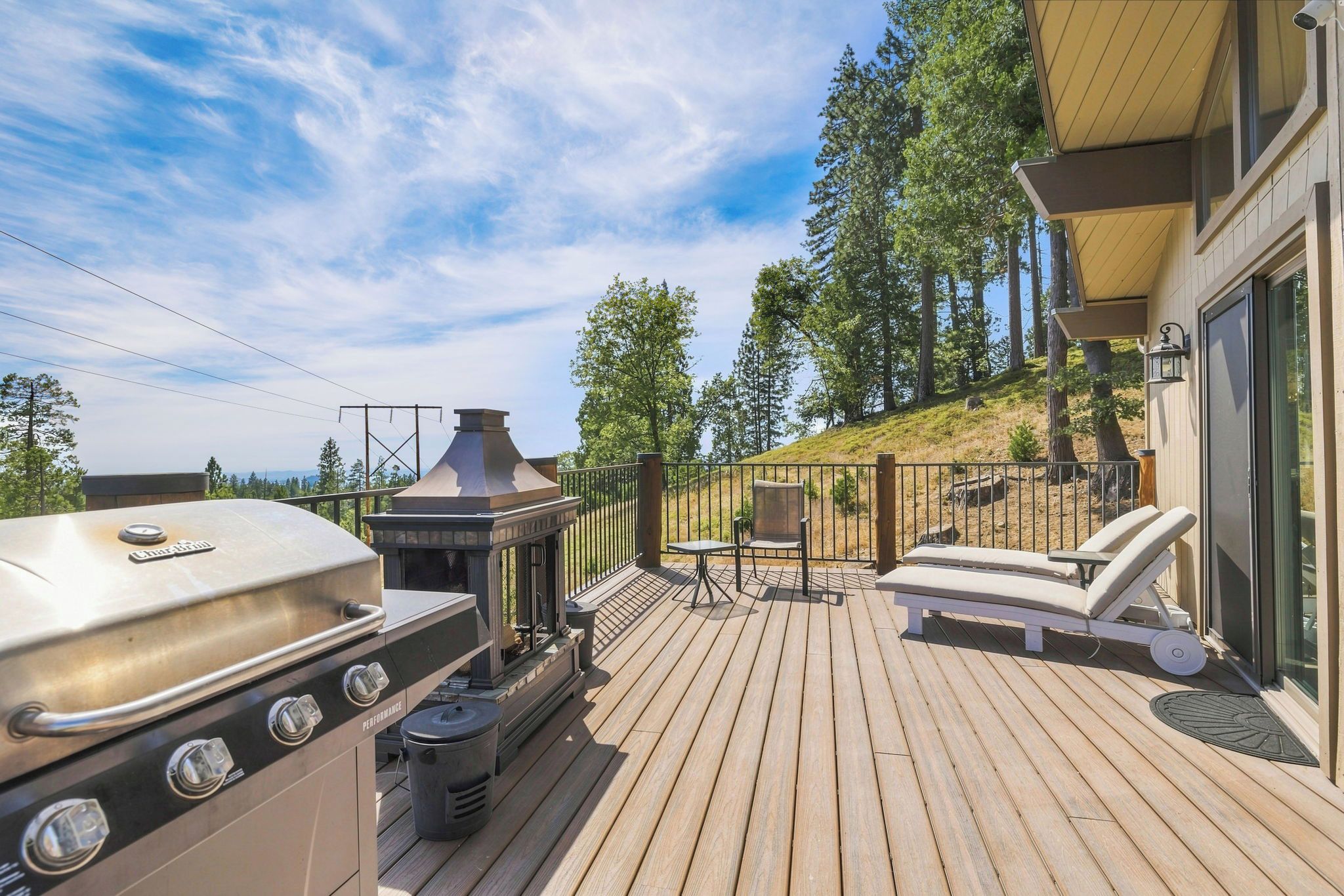 Eine Terrasse mit Grill, Gartenmöbeln und Blick auf den umliegenden Wald.