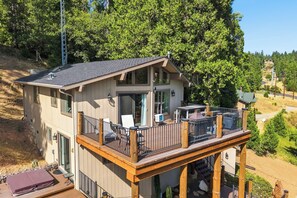 A two-story cabin with a balcony, a deck, and a view of the surrounding forest. - Hot Tub + Scenic Views: Luxury Twain Harte Cabin! (Twain Harte)