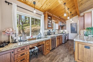 A kitchen with wooden cabinets, a marble countertop, and stainless steel appliances. - Hot Tub + Scenic Views: Luxury Twain Harte Cabin! (Twain Harte)