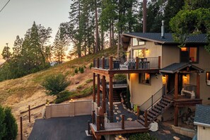 A multi-level house with a deck, outdoor seating, and a staircase leading to the upper levels. - Hot Tub + Scenic Views: Luxury Twain Harte Cabin! (Twain Harte)