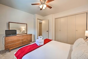 Une chambre d’hôtel comprenant un lit, une commode, un téléviseur, un ventilateur de plafond et une armoire.