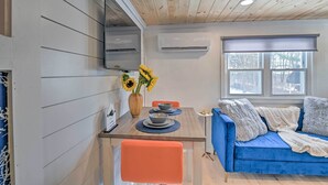 Eine moderne Küche mit Holzbalkendecke, einem Esstisch mit blauen Platzsets und einem blauen Sofa mit Decke.