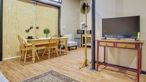 Un espacio habitable compacto con comedor, televisor sobre un escritorio y microondas al fondo.
