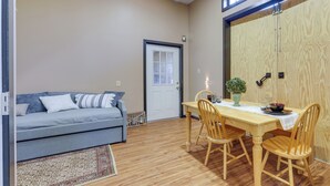 Una sala de estar acogedora con un sofá, una mesa de comedor con sillas y una puerta de madera.