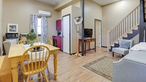 Amplia sala de estar con una mesa de comedor de madera, sillas, un sofá y una escalera.