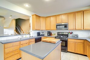 A modern kitchen with wooden cabinets, a granite countertop, a microwave, a stove, and a dishwasher.
