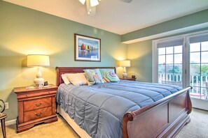 Quarto com uma cama grande, duas mesas de cabeceira com abajures, um quadro na parede e vista pela janela.