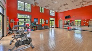 A gym with exercise equipment, large windows, and a red wall. - Naples Resort Townhome w/ Endless Amenities! (Naples)