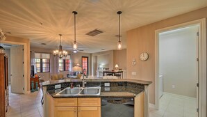 A kitchen with granite countertops, stainless steel sinks, and wooden cabinets. There are pendant lights hanging from the ceiling. - Naples Resort Townhome w/ Endless Amenities! (Naples)