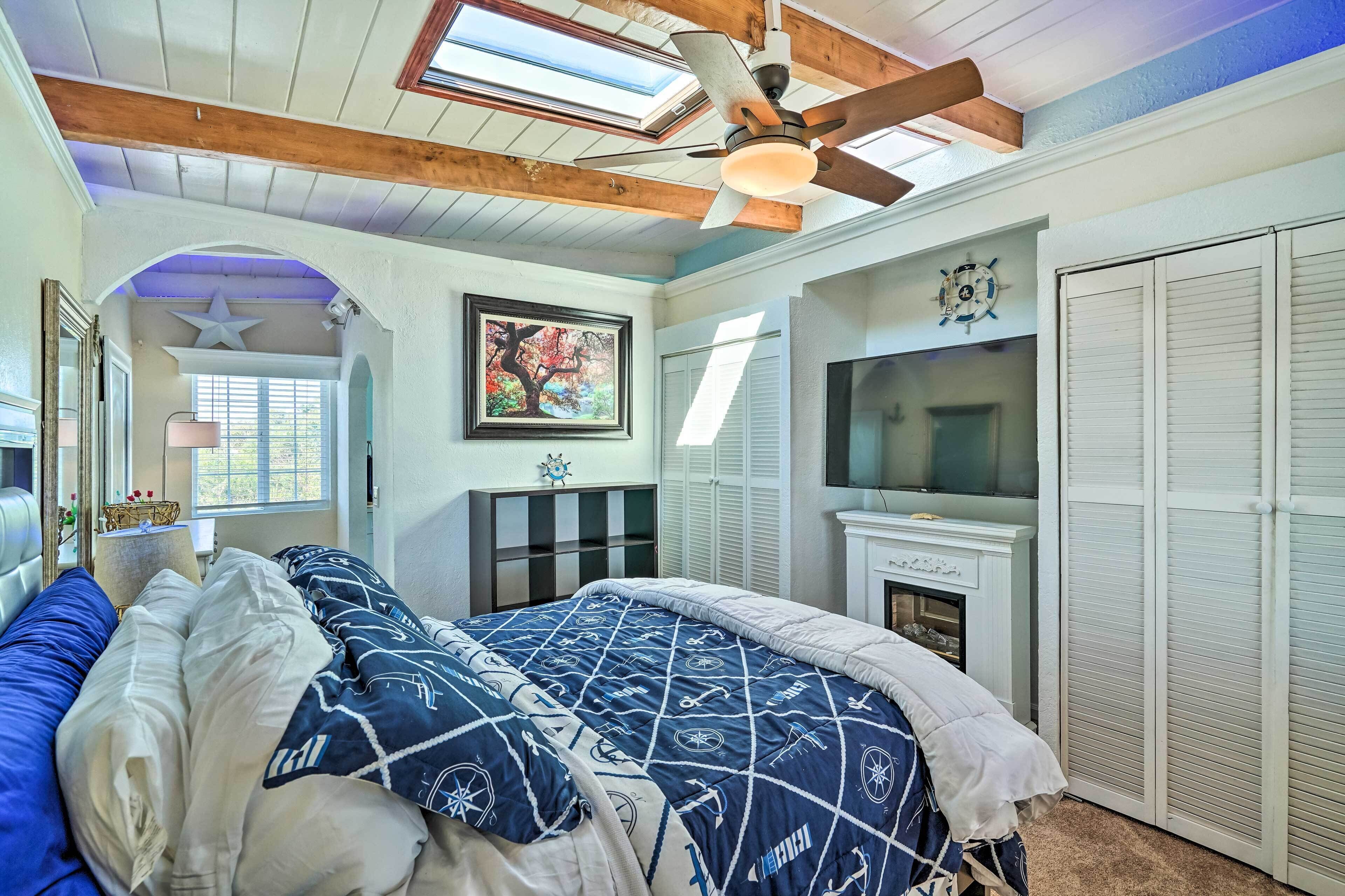 Une chambre à coucher avec un lit, un ventilateur de plafond, une cheminée et un téléviseur.
