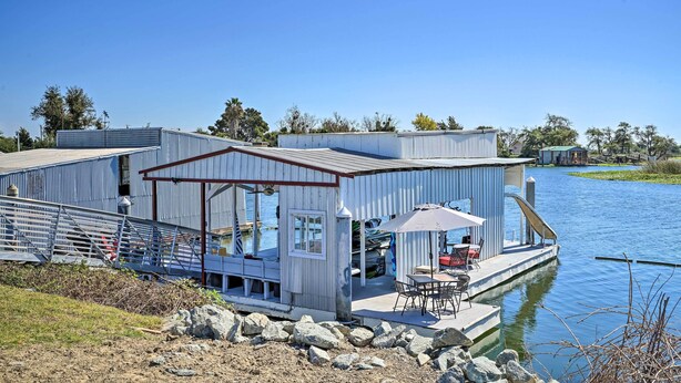A waterfront property with a dock, outdoor seating, and a covered patio area.