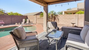 An outdoor patio area with wicker furniture, a glass table, and a pool. - Avondale Getaway < 8 Mi to Estrella Mountain! (Avondale)