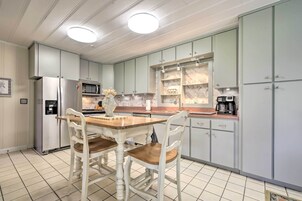 A modern kitchen with a central island, white cabinetry, and stainless steel appliances.