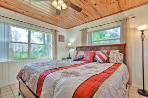 Cozy retreat with a large bed, wooden paneling, and a floor lamp.