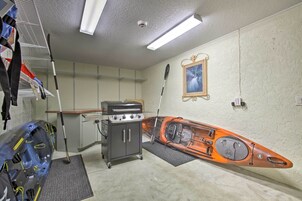 Quarto com um caiaque, churrasqueira e suporte para caiaques.