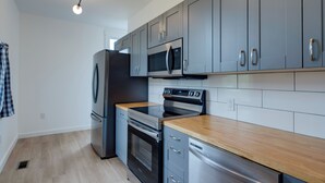 A modern kitchen with grey cabinets, stainless steel appliances, and a wooden countertop. - Modern Family Home in Mason w/ Backyard + Fire Pit (Mason)