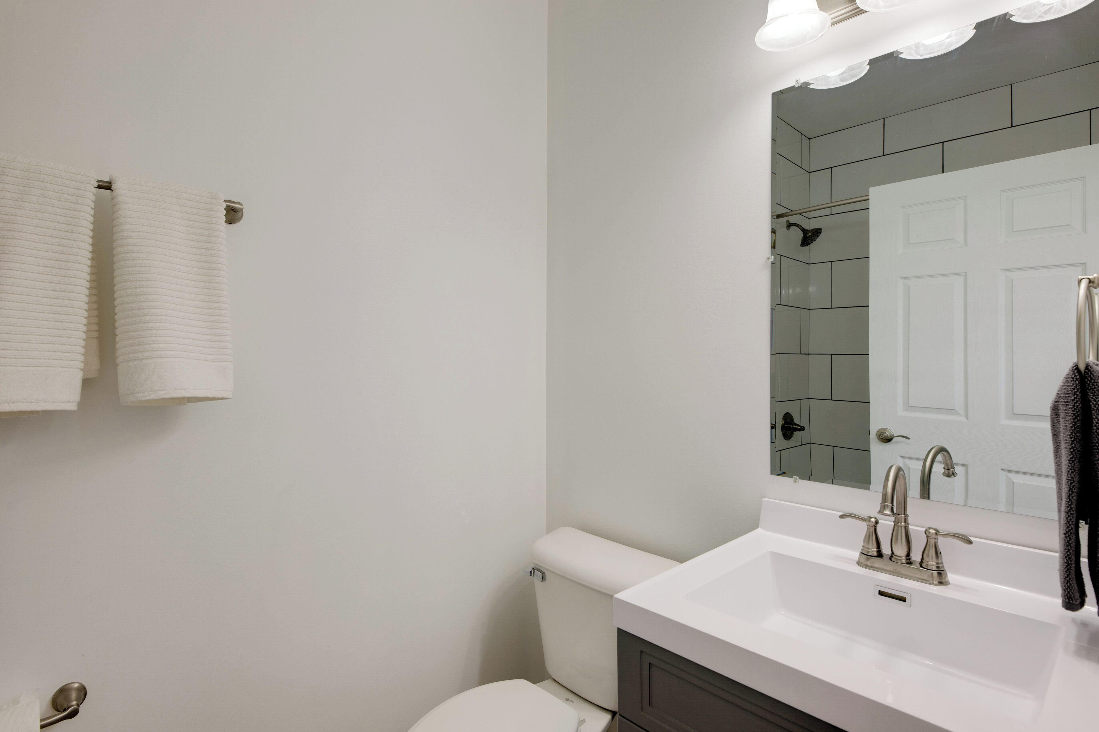 A bathroom with a white sink, a mirror, and a toilet.