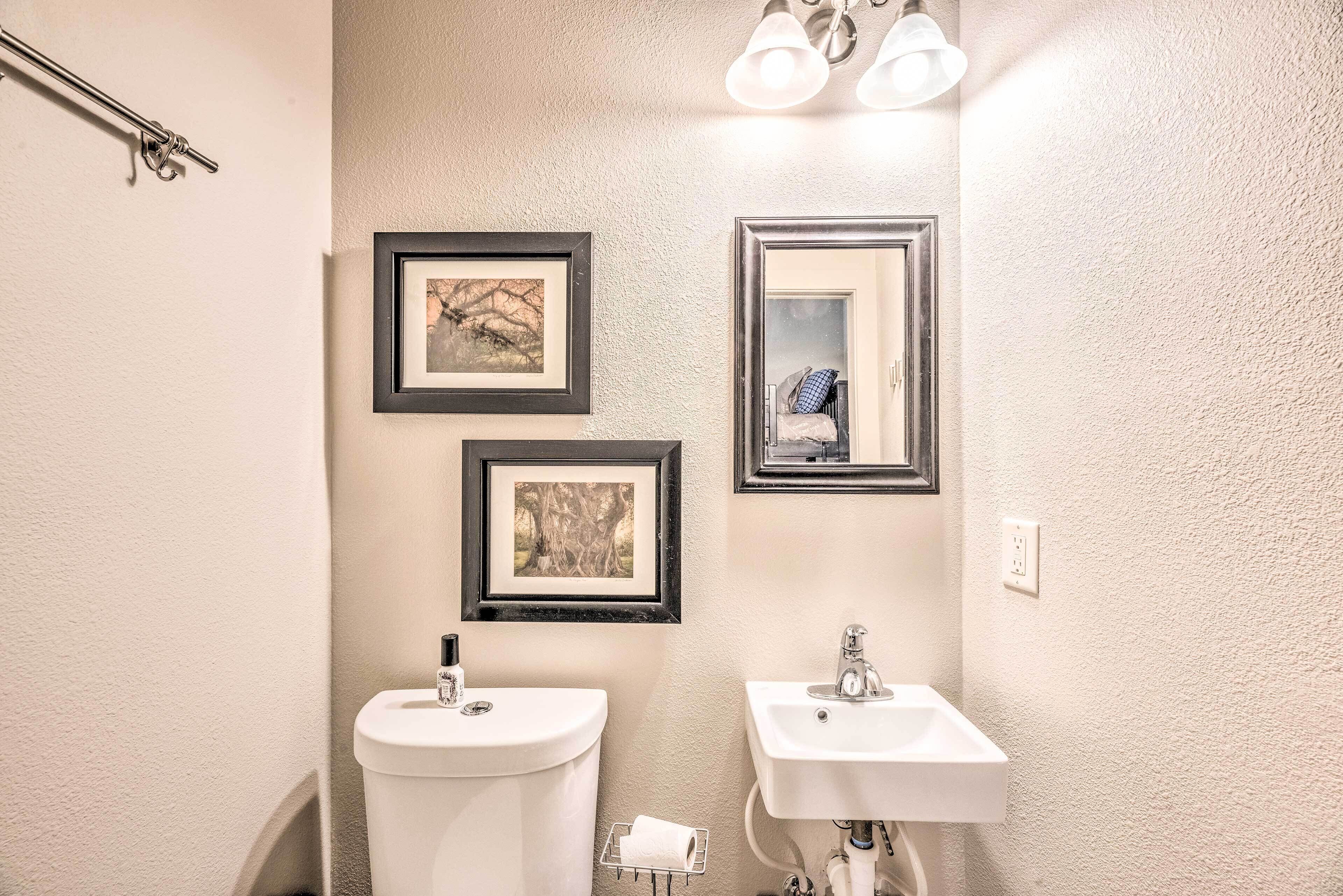 A bathroom with two sinks, a toilet, and framed pictures on the wall.
