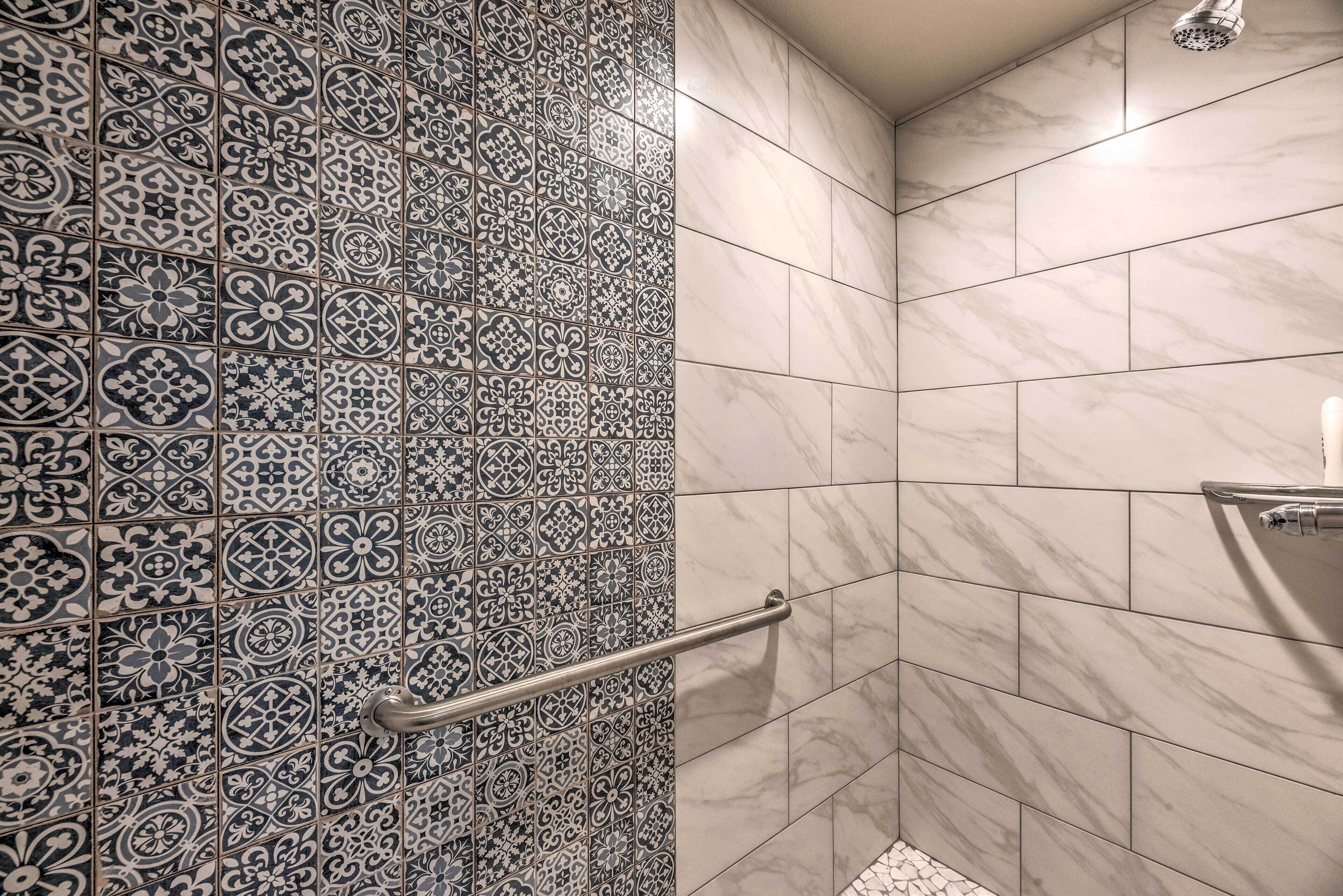 Un espace douche avec des carreaux à motifs sur un mur et des carreaux unis sur l’autre.