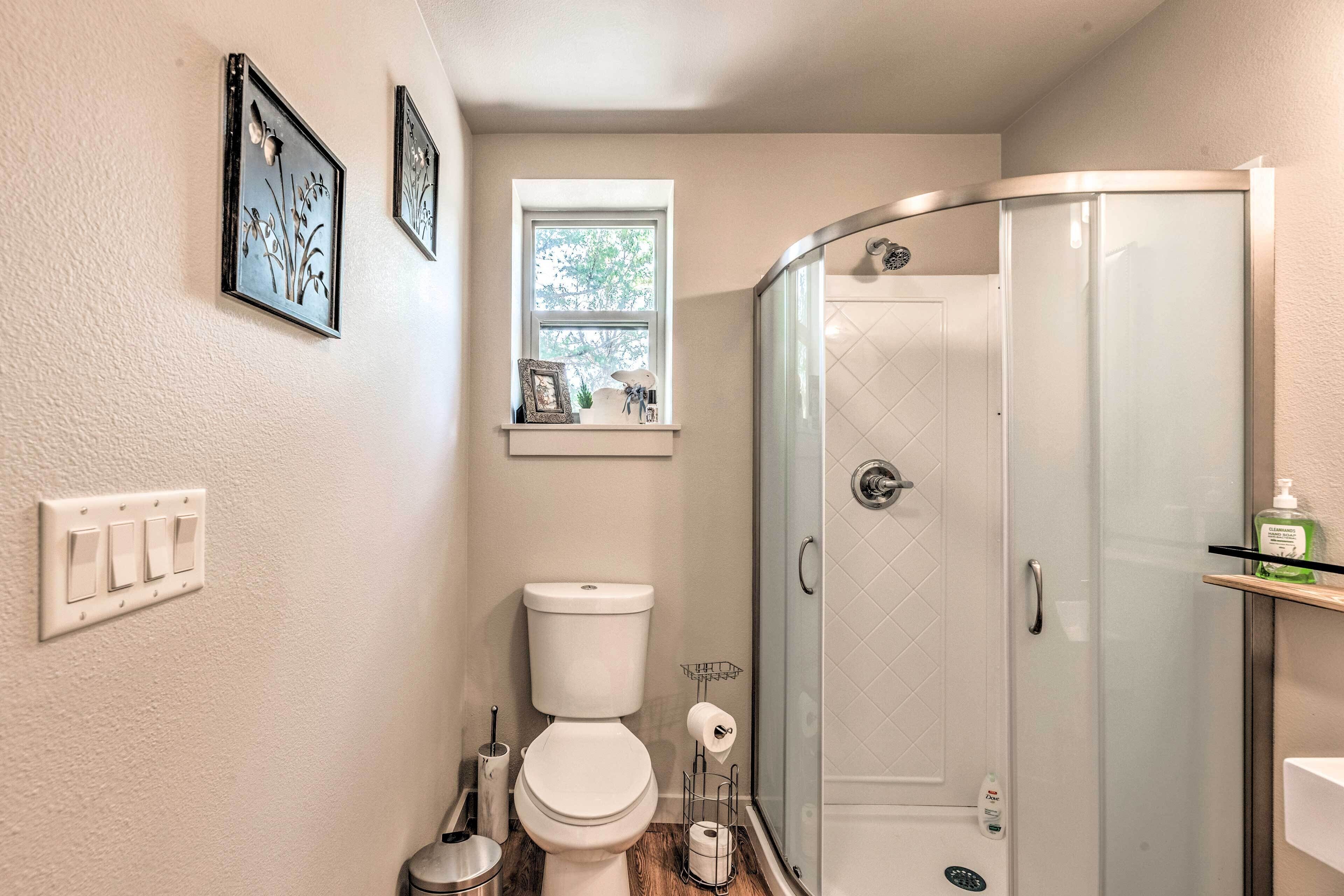 A bathroom with a toilet, a shower, and a window.