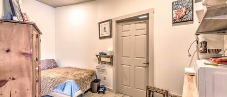 Ein Schlafzimmer mit einem Bett, einem Holzschrank, einer Tür und einem kleinen Regal mit Gegenständen.