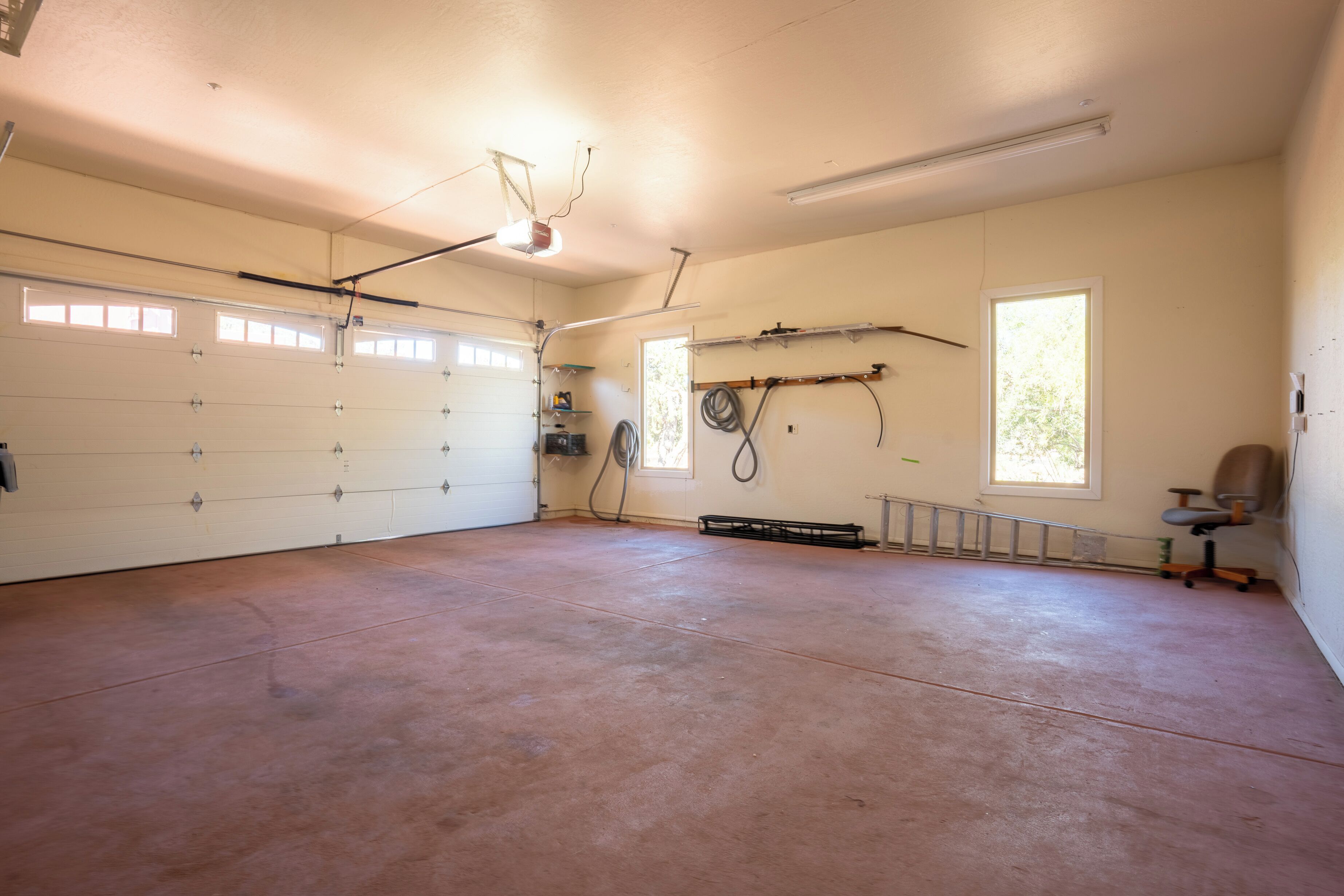 A spacious garage with a concrete floor, a white garage door, and a ceiling light fixture.