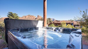 Un bain à remous doté d’une terrasse en bois et offrant une vue dégagée sur un paysage montagneux en arrière-plan.