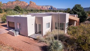 Une maison moderne de plain-pied, dotée d’un garage, de grandes fenêtres et d’un espace patio.