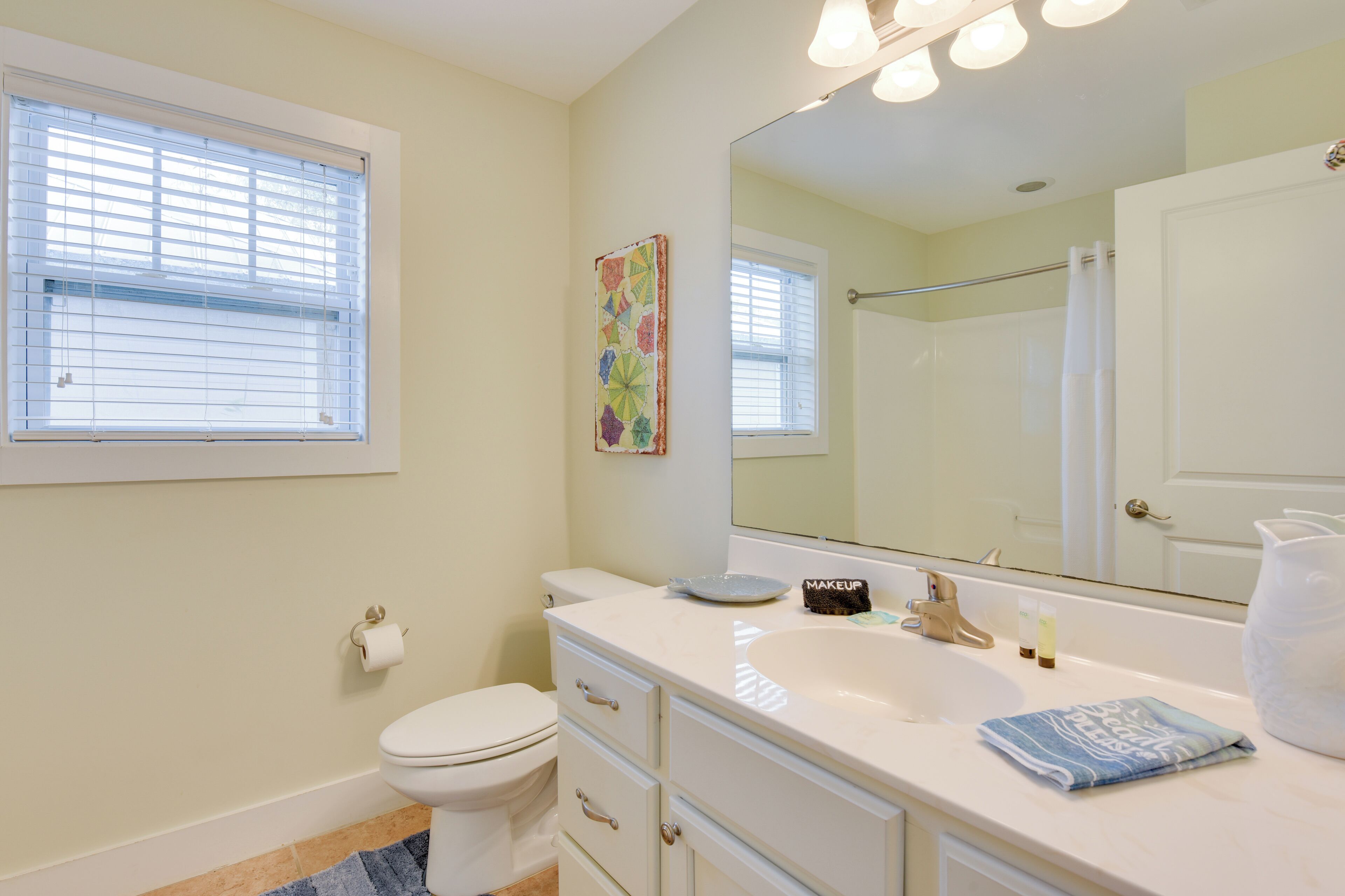 Une salle de bain équipée de toilettes, d’un lavabo, d’un miroir et d’un porte-serviettes.
