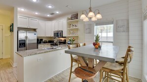 A modern kitchen with white cabinetry, stainless steel appliances, and a central island with seating. - Sunny Santa Rosa Beach in 30 A Neighborhood! (Santa Rosa Beach)