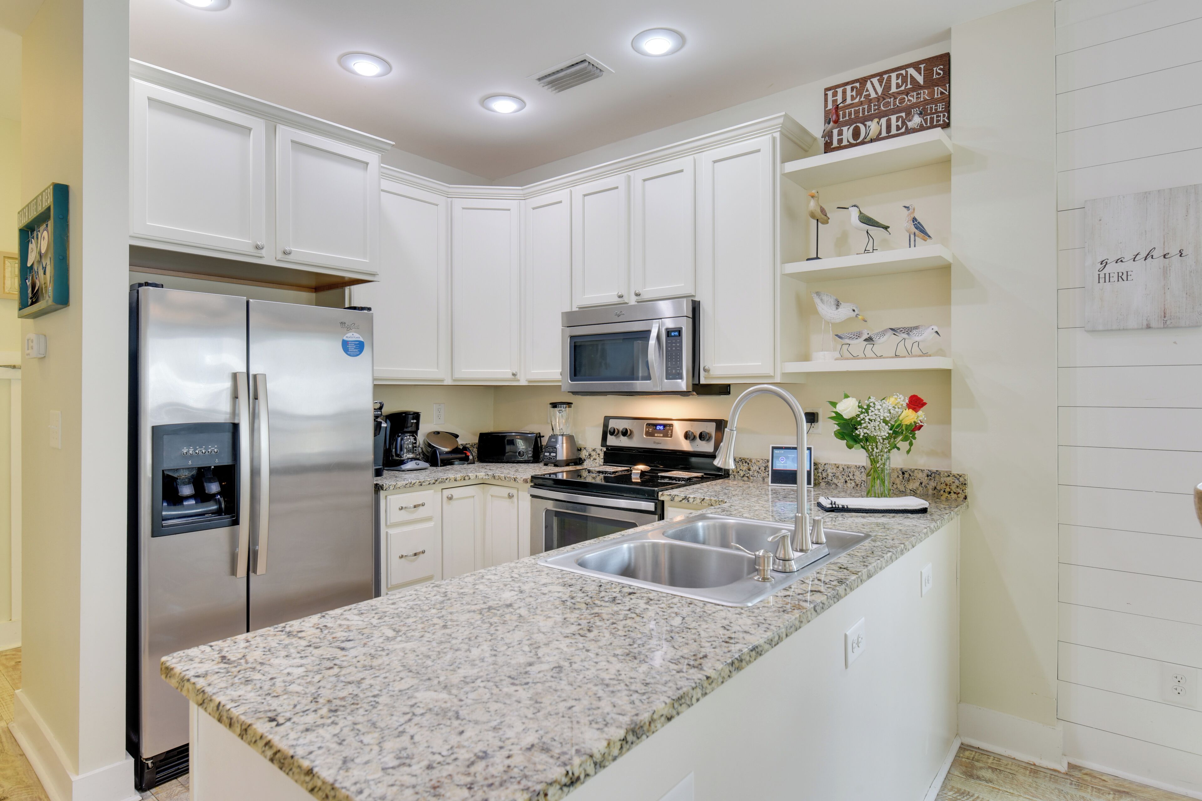 A modern kitchen with white cabinets, stainless steel appliances, granite countertops, and a built-in microwave.