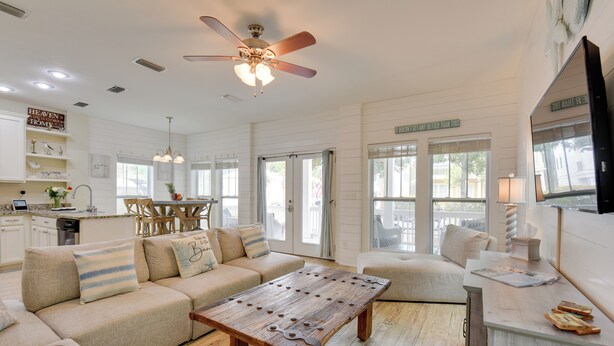 A spacious living room with a wooden coffee table, beige sofas, and a dining area with a wooden table and chairs. - Sunny Santa Rosa Beach in 30 A Neighborhood! (Santa Rosa Beach)