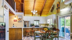 A kitchen with wooden flooring, a dining area with a table and chairs, and a view of the outdoors through a sliding glass door. - Groveland Home - Walk to Pine Mountain Lake! (Groveland)