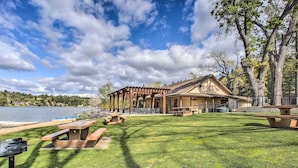 A lakeside outdoor area with picnic tables, a pergola, and a building with a sign. - Groveland Home - Walk to Pine Mountain Lake! (Groveland)