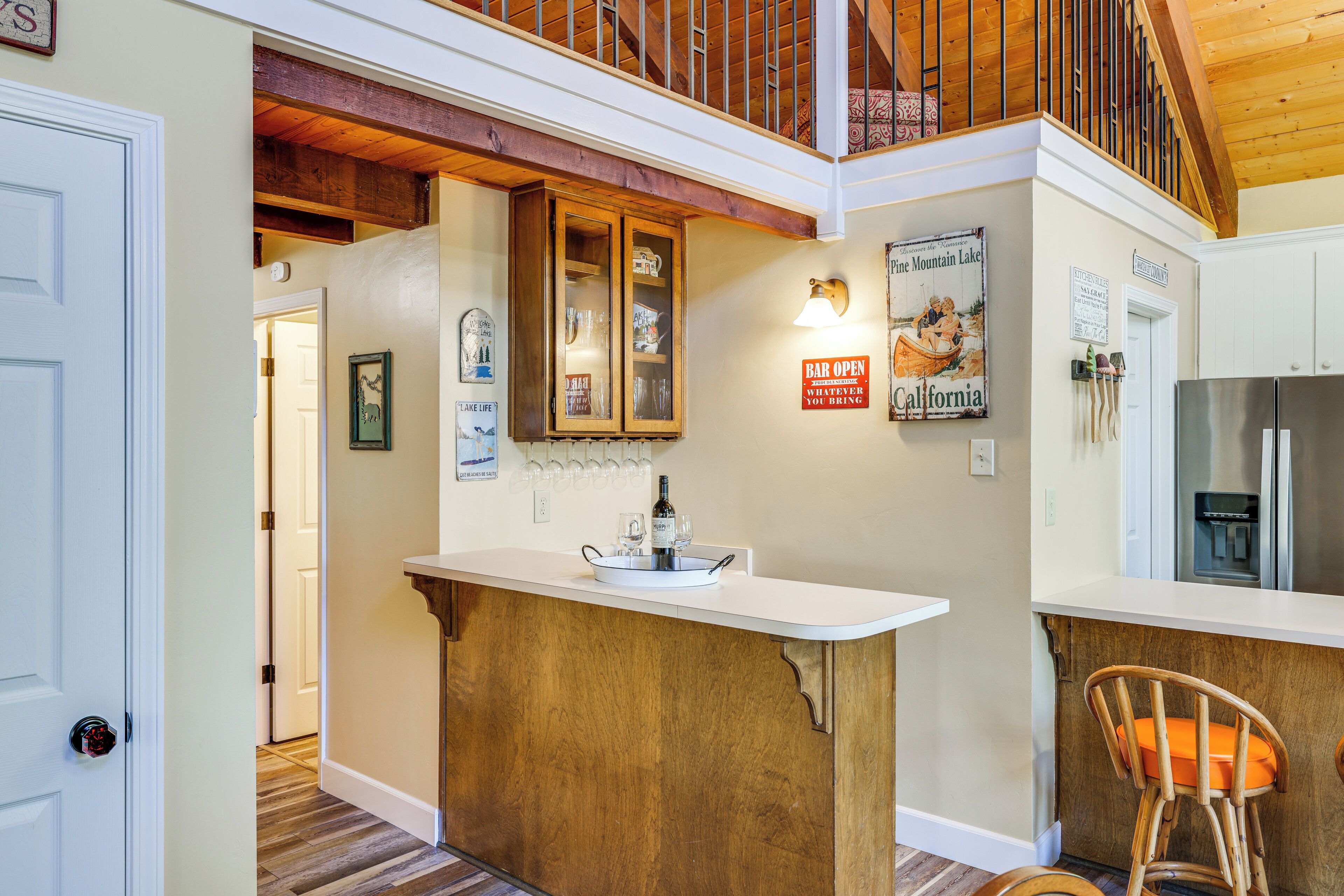 A kitchen with a wooden island, a bar sign, and a refrigerator.