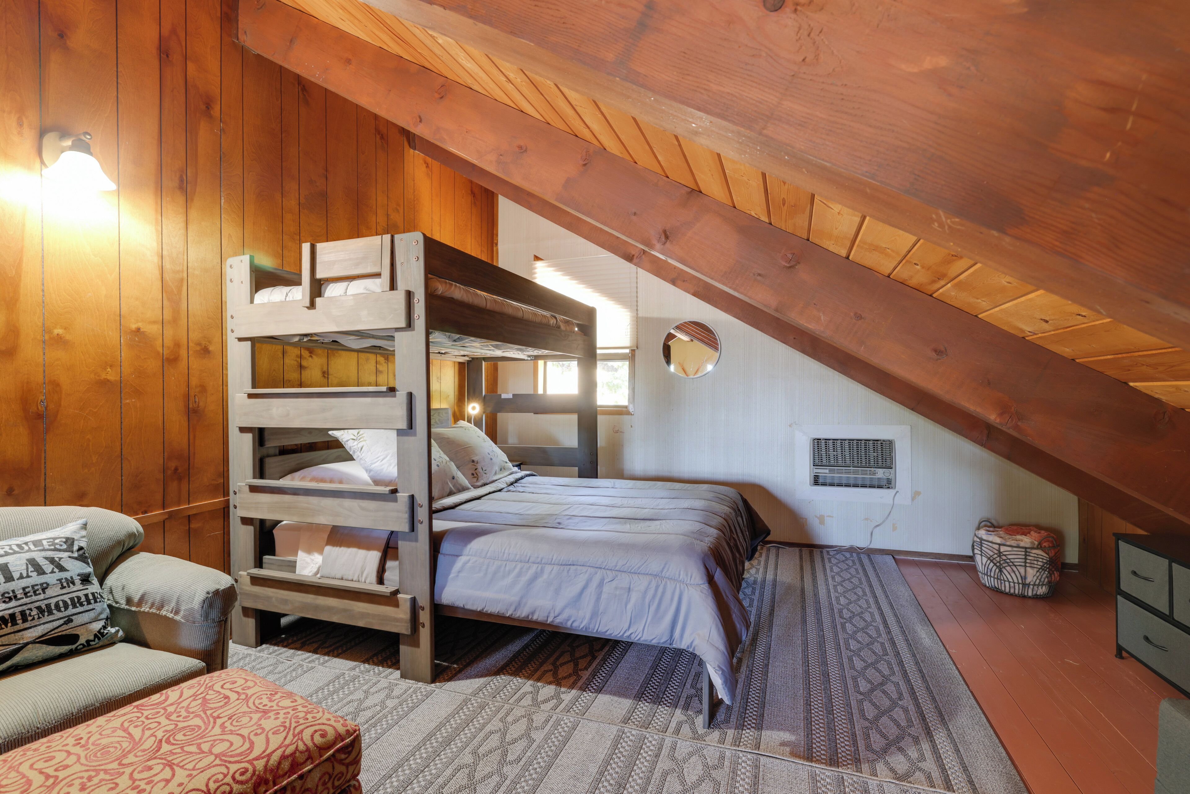 A cozy attic bedroom with a bunk bed, a sofa, and a patterned rug.